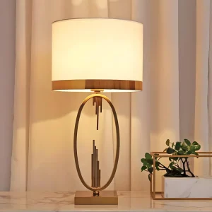 Elegant bordslampa med oval ram i guld och vit tygskärm